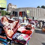 A vendor displaying blanket to a customer at Bacha Khan Chowk.