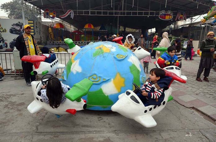 Children enjoy a swing during a fun fair for journalists’ families at Chacha Younas Park, arranged by the Press Club