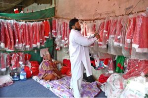 A vendor is arranging and displaying Santa Claus dresses in connection with the upcoming Christmas celebrations at a stall in the G-7 area of the Federal Capital