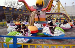 Children enjoy a swing during a fun fair for journalists’ families at Chacha Younas Park, arranged by the Press Club