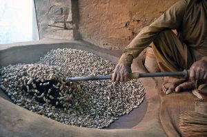 A worker busy roasting peanuts at his workplace in a local market
