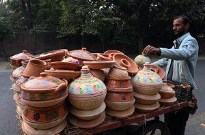A vendor displays and sells traditional earthenware on a handcart along the roadside.