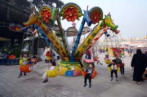 Children enjoy a swing during a fun fair for journalists’ families at Chacha Younas Park, arranged by the Press Club
