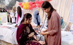 A health worker checks students’ blood pressure at a wellness camp at Government College Women’s University, Madina Town.
