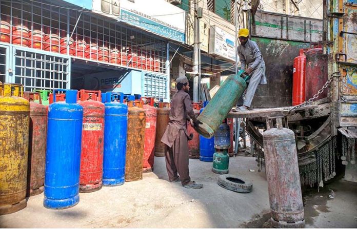 Labourers are busy unloading gas cylinder from delivery truck at shop in Ghouri Town