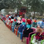 Colorful handmade dolls are displayed on small plastic chairs along a roadside for sale to attract customers.
