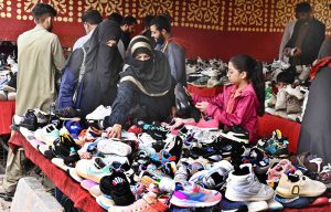 Women purchasing jogger shoes from a vendor at Makki Shah Road.