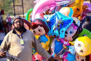 A street vendor walks through the streets carrying cartoon-shaped balloons to attract young buyers in the federal capital.