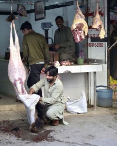 A butcher removes the skin of a goat after slaughtering it, preparing fresh meat for customers at his shop in the Banni area of the twin cities