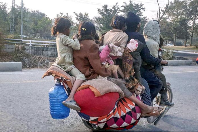A nomad family travels with their belongings on a motorcycle along the Expressway in search of a place to settle in the federal capital