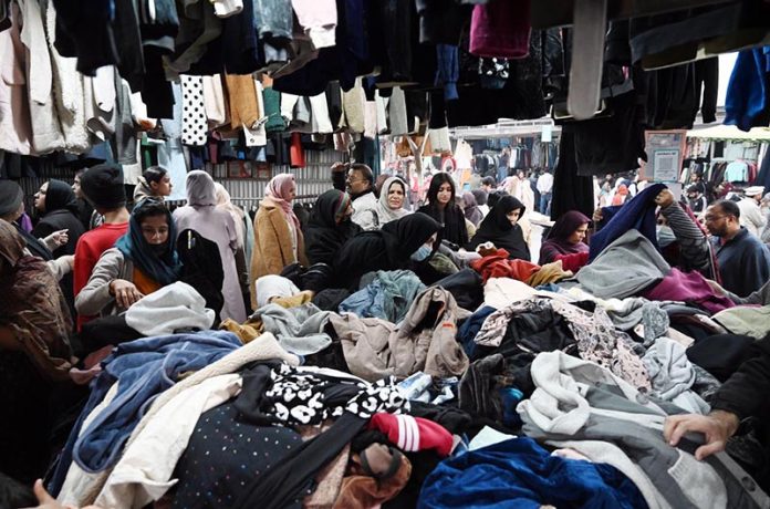 People busy selecting and purchasing second hand clothes from vendor at H-9 weekly Bazaar in the Federal Capital