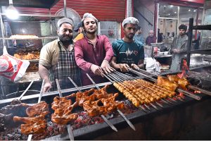 A street food vendors prepare BBQ, including special seekh kebabs and chicken tikka, over charcoals at Mazang Road.