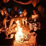 Citizens warm themselves around a fire to beat the cold at Jinnah Colony