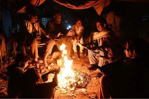 Citizens warm themselves around a fire to beat the cold at Jinnah Colony