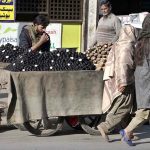 A street vendor sells water chestnuts and yams from his handcart to attract passersby in the Banni area of the twin cities