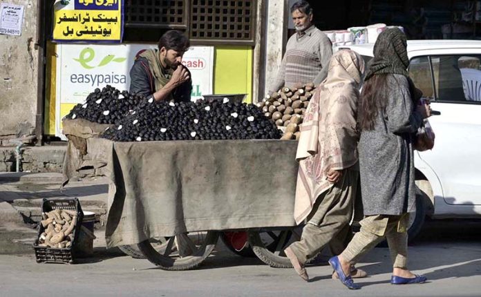 A street vendor sells water chestnuts and yams from his handcart to attract passersby in the Banni area of the twin cities
