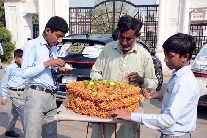 Students purchase spicy lentils and dry noodles from a vendor at a local market