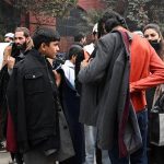 People buy coats and jackets from vendors along roadside.
