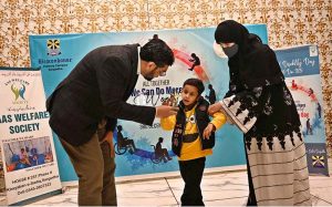 Renowned child specialist Dr. Khawaja Arshad awards a differently-abled child during a ceremony held in connection with the International Day of Persons with Disabilities organized by Adil Special School and Rehabilitation Center at a private hotel