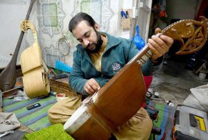 A skilled person repairing traditional musical instrument Rabbab at his workplace near Dabgari area.