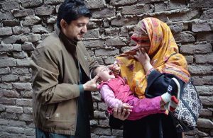 Polio Health workers administering polio drops to a child during a door-to-door polio vaccination campaign in the Provincial Capital.