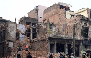 Workers demolish buildings along the road to widen Data Darbar Road.