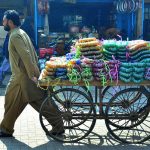 A cart holder transports bangles to the local market along Cloth Market Road