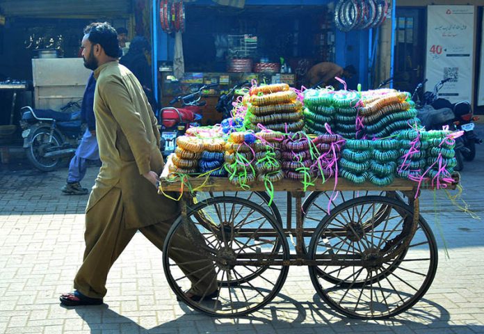 A cart holder transports bangles to the local market along Cloth Market Road