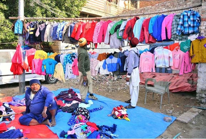 Customers are selecting to buy second-hand jackets from a roadside vendor in Latifabad as the mercury level is dropping day by day during the winter season
