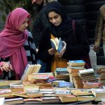 Girls selecting and buying old books from a stall on Mall Road