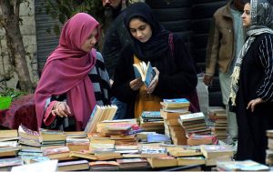 Girls selecting and buying old books from a stall on Mall Road