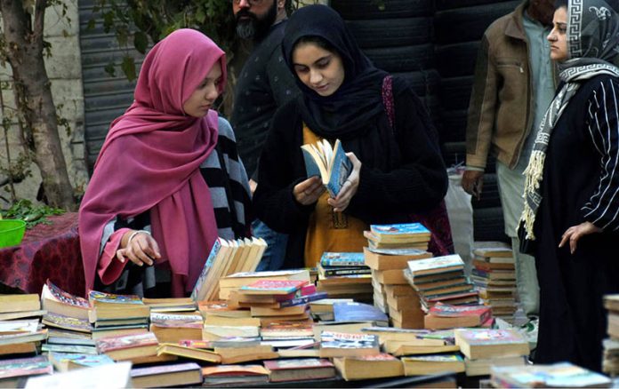 Girls selecting and buying old books from a stall on Mall Road