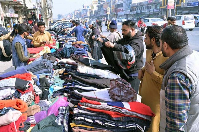 People purchasing second-hand clothes from roadside vendors to keep them warm and battle the winter chill