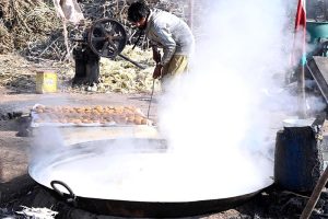 Farmers busy boiling sugarcane juice to prepare traditional sweet products, Jaggery (Gurr) and brown sugar (Shakkar), at their farm on the outskirts of the provincial capital