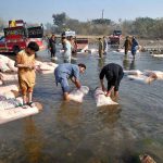 Laborers wash sacks of vegetables in a local stream near Phandu area before taking them to the market