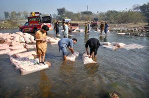 Laborers wash sacks of vegetables in a local stream near Phandu area before taking them to the market