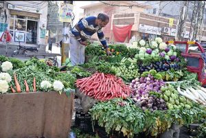 A vegetable vendor arranges fresh vegetables to attract customers at his roadside stall in the city