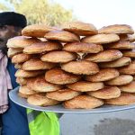 A street vendor carries bakery item delicious puff for sale while walking through the streets of Kambar Road
