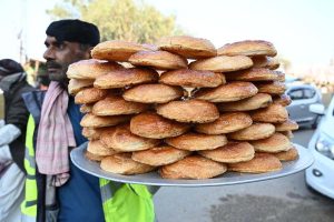 A street vendor carries bakery item delicious puff for sale while walking through the streets of Kambar Road