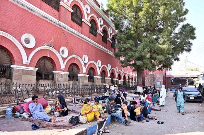 A large number of patient relatives wait on the footpath outside a Civil Hospital ward due to limited space for attendants inside