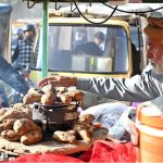 A vendor sells hot roasted yums drizzled with spicy sauce from his cart near Rahmatul-il-Alamin Park, Satellite Town