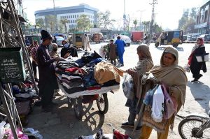 Women buy second-hand clothes from a vendor’s cart along the roadside.