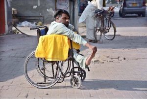 A differently-abled vendor waits in his wheelchair for customers along the roadside, displaying dusters on his cart for sale on the occasion of the International Day of Persons with Disabilities
