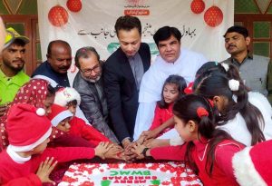 Deputy Commissioner Syed Hassan Raza cuts a Christmas cake with members of the Christian community and children at Islami Colony. APP/HBR/FHA
