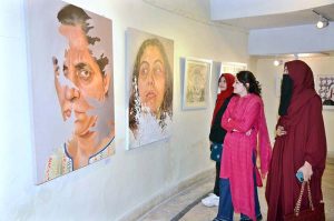 A group of female students observe paintings during the exhibition arranged by Government College Women University Faisalabad at Punjab Art Council.