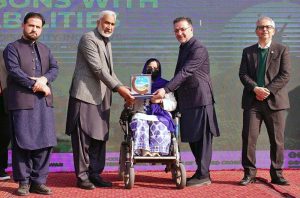 Provincial Health Minister Mian Khaleeq-ur-Rehman, along with the heads of the ICRC and the Paraplegic Centre, presents an appreciation shield to a young differently-abled participant during the International Day of Persons with Disabilities at the Paraplegic Centre