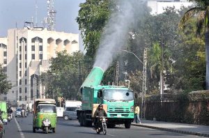 An anti-smog vehicle sprays water on trees along Egerton Road.