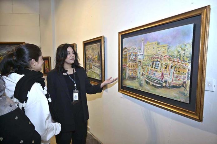Visitors taking keen interest in an artwork by an artist BARKAT on special needs, who graduated as Fine Artist from NCA Lahore, on display at the NCA Islamabad Campus during an exhibition on the eve of International Day of persons with Disabilities