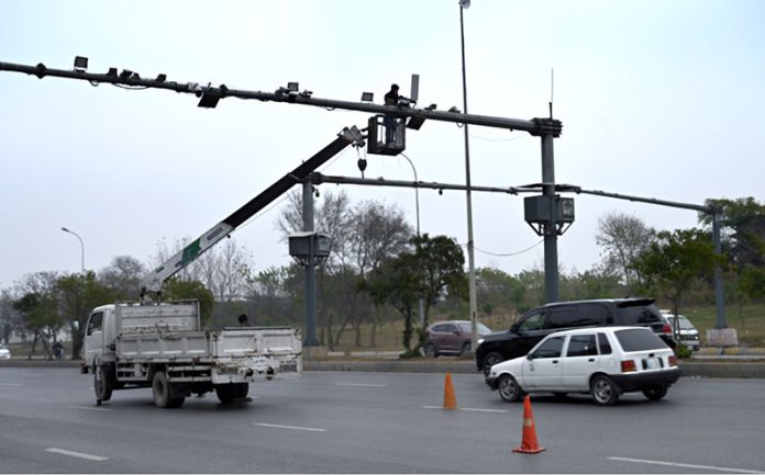 A worker is busy repairing CCTV cameras during maintenance work along Srinagar Highway in the Federal Capital