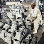 A craftsman arranges freshly molded concrete pillar capitals at a roadside workshop, where decorative architectural elements are being prepared for construction use